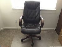 Front view of brown faux leather executive office chair showing padded seat and button-tufted backrest.