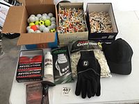 Photo of the golf items showing golf balls, tees, gloves, cap, ball cleaner, and divot tool