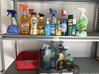 Shelf of assorted household cleaning products including sprays, pump soap, and liquid cleaners