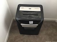 Front view of a large black and silver Staples paper shredder with control buttons and paper feed slot visible.