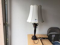 Photo of the entire table lamp showing the white silk scalloped lampshade and decorative metal base