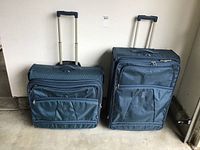 Front view of two blue Travel Pro wheeled suitcases with telescoping handles retracted, showing zippered compartments and carrying handles