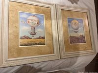 Photo showing two framed air balloon prints by Alexandra Churchill on a flat surface.