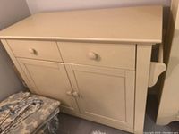 Front view of the pale hay coloured wooden change table/cabinet showing two drawers above and two cabinet doors below, all with round knobs. Visible staining marks present.
