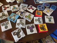 20 assorted fidget spinners in original boxes on a table, showing a variety of colors and packaging styles.