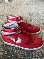 Side view of red Nike high top sneakers showing white swoosh and Velcro strap detail on ankle collar.