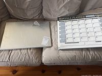 Magnetic board and laminated monthly planner whiteboard shown side by side on fabric surface