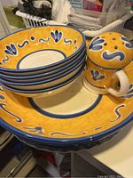 Full view of entire set showing large serving bowl, four smaller pasta bowls stacked, and Parmesan cheese container, highlighting hand-painted yellow and blue floral patterns.