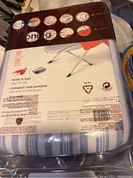 Photo of the tabletop ironing board in original packaging showing folding legs and striped cover