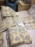 Photo showing the toile crib skirt, small pillow, and bumper pad on a chair and couch.