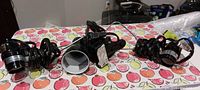 Three black plug-in hanging light fixtures with their cords coiled, placed on a table with a decorative tablecloth.