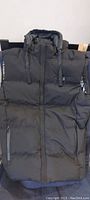 Front view of large black insulated heated vest with zippered pockets and high collar.