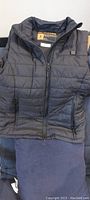 Black quilted heated vest with zipper front and pockets, size small.