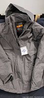 Grey hooded heated jacket shown laid out with front zipper and hood visible, tagged with Kabcon brand label.