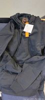 Full view of the large black heated hoodie sweatshirt laid on a surface.