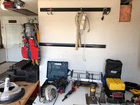 Overview of all tools and extension cords on a table and bench in garage environment.