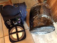 Black insulated picnic hamper with plates, cutlery and glasses inside.