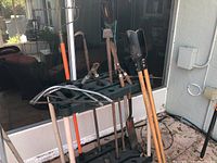 Full view of Rubbermaid rack with various yard tools including pruning saws, rakes, shovel, post hole digger, loppers, and hedge trimmers.
