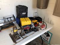 Photo of RV tools and supplies on a white folding table, including hydraulic jacks, canopy blocks, and various connectors