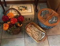 Photo showing full lot including Longaberger basket with artificial flowers, decorative fabric-lined basket, and floral decorative trunk.