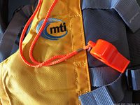 Close-up of yellow and gray MTI life jacket with visible embroidered MTI logo and orange whistle on an orange lanyard.