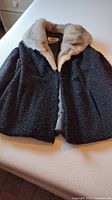 Full view of dark textured vintage jacket with fur collar laid flat showing overall condition and style.