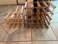 Two wooden wine racks side by side on tile floor, showing size difference and overall structure.