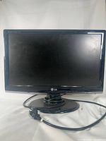 Front view of the 18 inch LG television monitor powered off, showing screen, bezel, and stand with attached power cable.