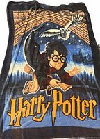 Photo of large Harry Potter blanket showing Harry flying on a broomstick, with owl and night sky background, and 'Harry Potter' lettering.