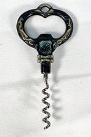 Top view of metal bottle opener with corkscrew showing grapevine motifs and heart-shaped handle