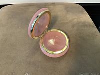 Open view of vintage pink alabaster dresser jar showing the hinged lid and gold trim inside and out with polished surface.