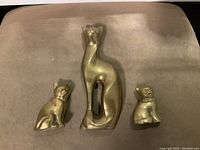 Top view of three brass cat figurines: one larger mother cat and two smaller baby cats.