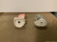 View of bottom of two cat salt and pepper shakers showing holes and some damage
