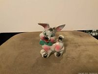 Front view of vintage ceramic bunny figurine showing blue bow and painted details.