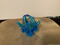 Front angle of blue vintage chalet glass basket showing split handle and outward flared design