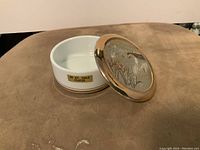 Open view of the white porcelain dish and the gold plated lid with embossed swan design, showing interior and original sticker on side.