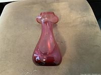 Front view of the vintage cranberry glass vase showing the bulbous body and rippled rim.