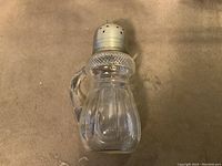 Clear glass muffiner with vertical panels, handle on side, and domed perforated silver plated lid with finial top.
