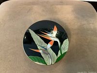 Close-up of one Otagiri coaster showing hand painted Birds of Paradise flower on black background.