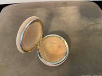 Inside view of the open yellow alabaster trinket box showing the smooth interior and metal rim on the lid.