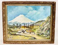 Frontal photo showing the full oil painting with ornate carved frame depicting a mountain, rustic houses, trees, and sky.