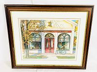 Full view of framed print with mat and glass showing a colorful apothecary storefront with bicycle and autumn trees.