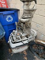 Side view of vintage outboard boat motor showing mounting bracket and propeller with dirt and wear.