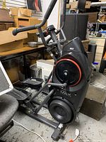 Front-left angle view showing main frame, flywheel housing, pedals and console