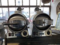 Two Castle sterilizers side by side on a table with visible heat gauges, timer dials, and locking arms.