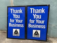 Two rectangular metal signs with blue background and white text 'Thank You for Your Business' with Citgo logo at bottom, leaning against a wall.