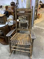 Front view of the Cracker Barrel wooden rocking chair showing the slatted seat and vertical spindle backrest.
