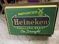 Front view of Heineken bar light sign with green background, gold and white lettering, windmill logo.