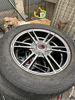 Single Kosei alloy wheel with tire resting on a stack outdoors, showing face and sidewall wear