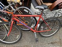 Left side view of red Mongoose mountain bike, showing the frame, rear basket, and tires